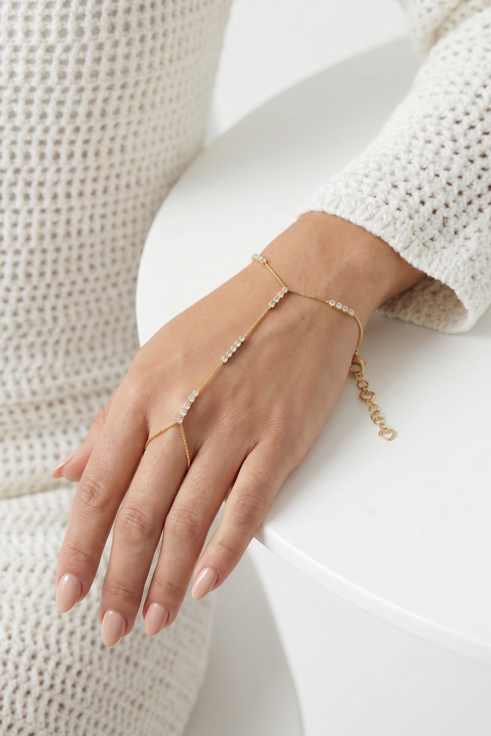 Hand wearing a delicate gold bracelet on a white background