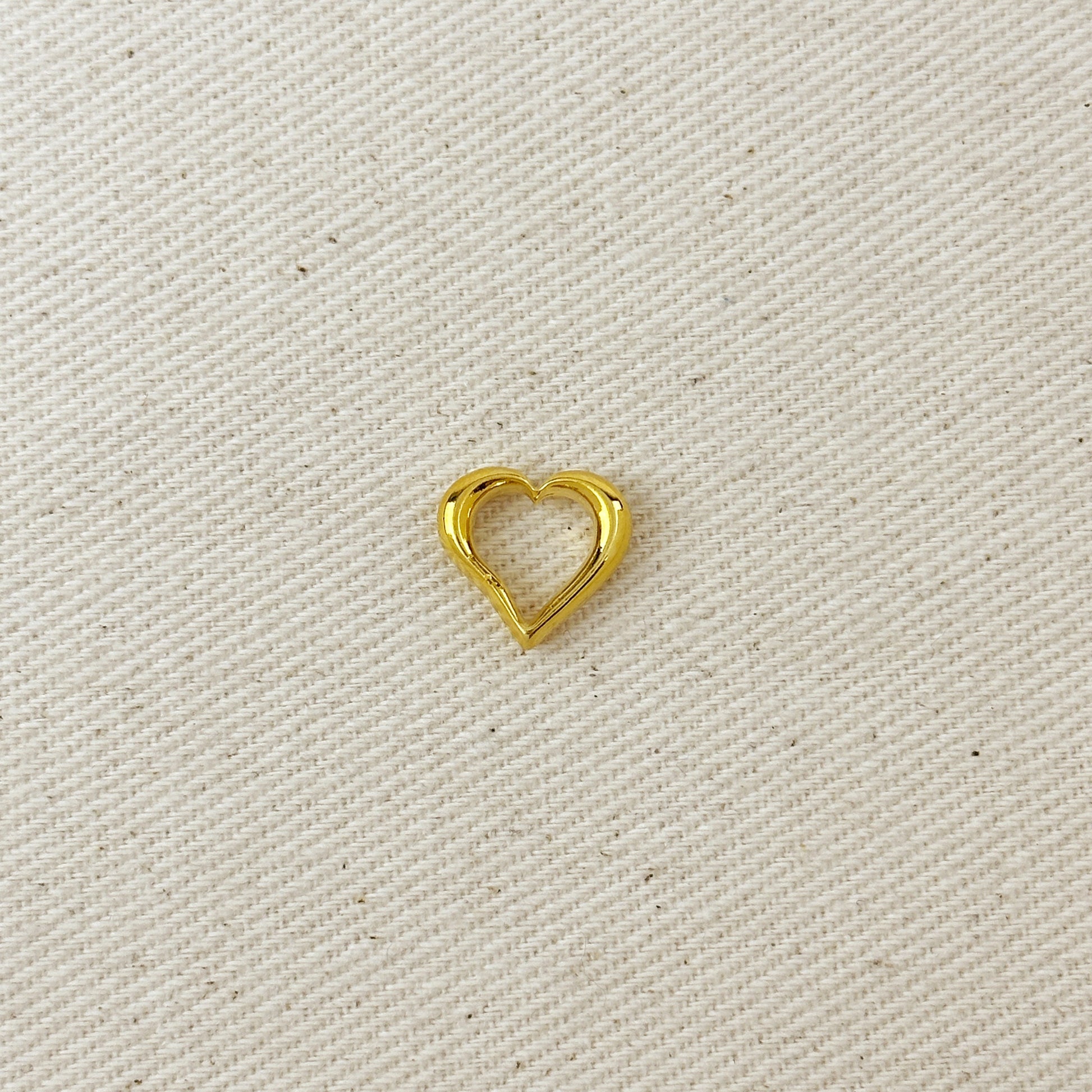 Gold heart-shaped charm on a beige fabric background